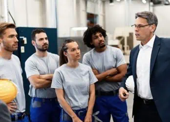 Company manager giving presentation to group of workers in a factory.