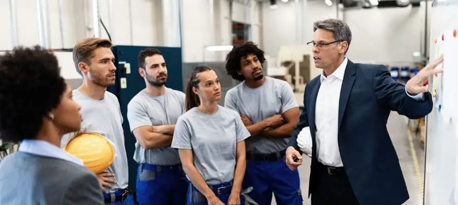 Company manager giving presentation to group of workers in a factory.