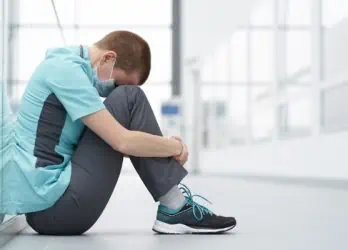 healthcare employee sitting with head between knees