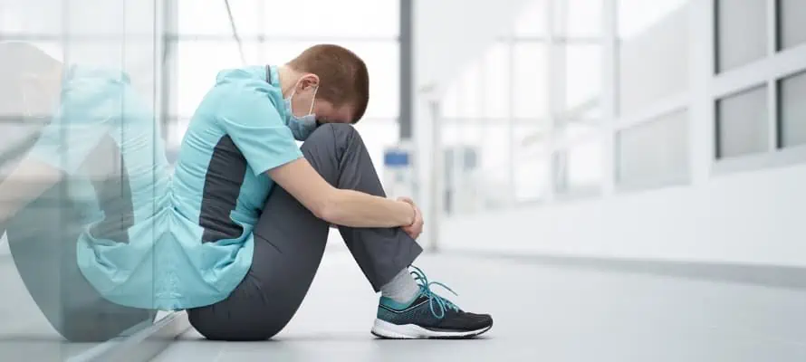 healthcare employee sitting with head between knees