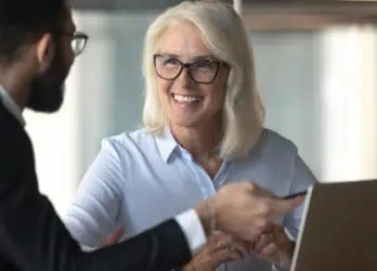 two professionals talking and working at laptop