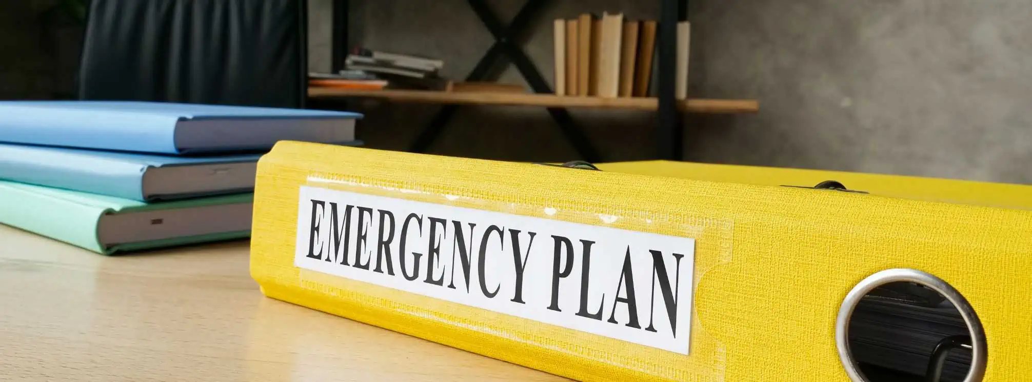 Yellow binder on a desk that says "emergency plan" on it.