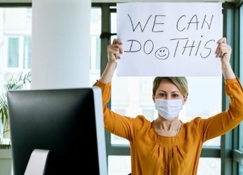 businesswoman wearing a medical mask holding up sign