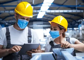 two manufacturing workers wearing masks and hard hats