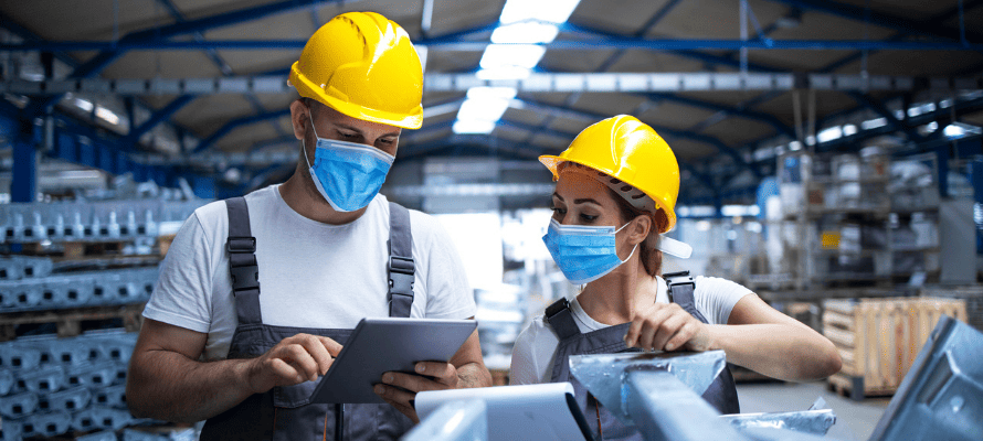 two manufacturing workers wearing masks and hard hats
