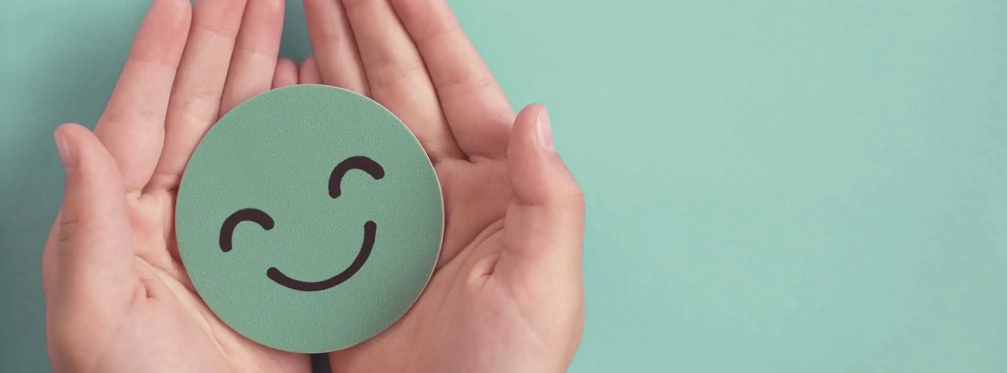 hands holding a green paper cutout of a smiley face