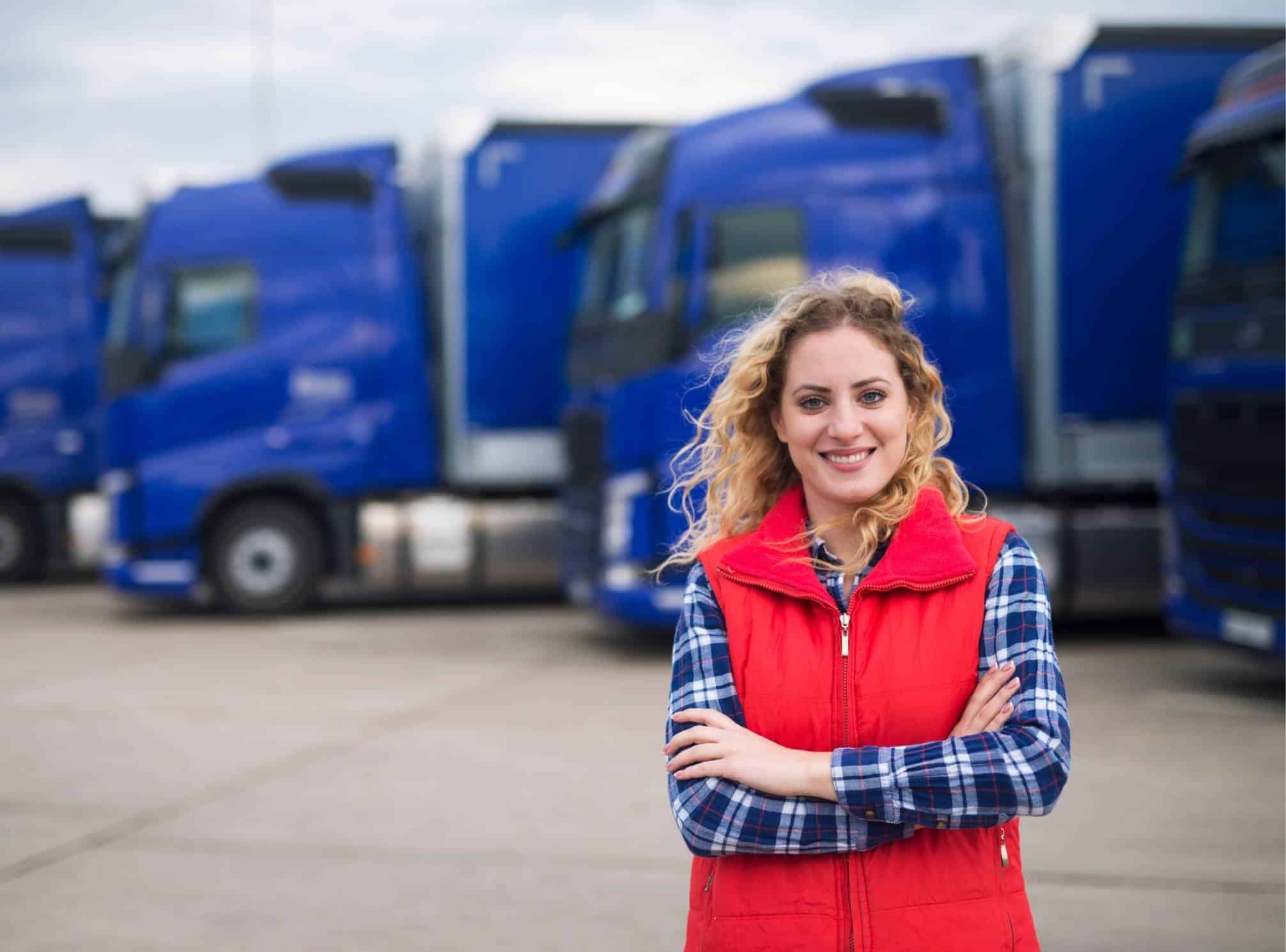 female logistics employee standing in front of trucks