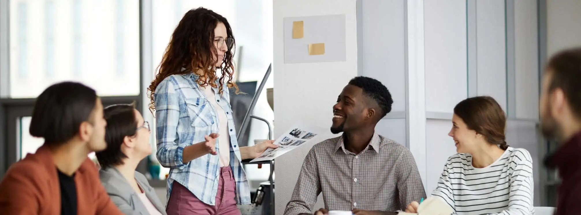 woman speaking to a group of coworkers at a cross-departmental meeting