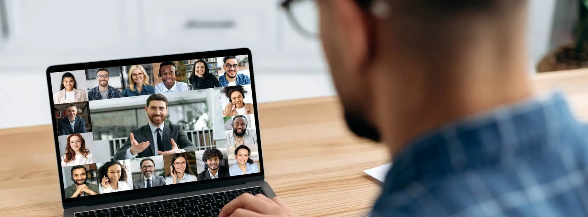 remote employee watching the company town hall on his laptop with the CEO communicating with everyone