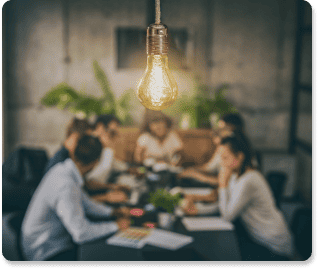 illuminated lightbulb hanging above a table of professionals working on an internal communication strategy