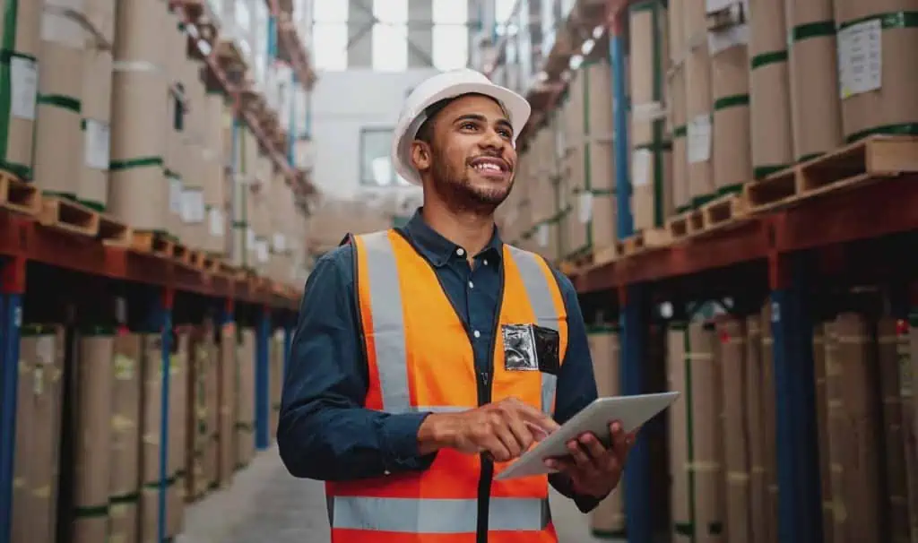 male warehouse worker in a hard hat with an ipad