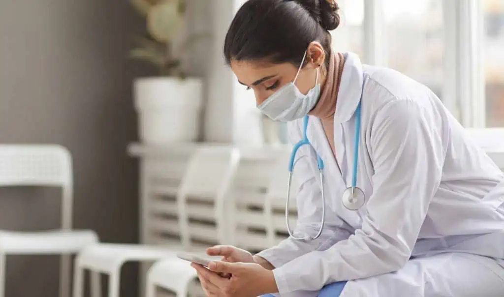 female nurse in a face mask using her phone