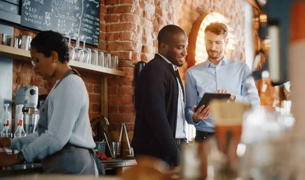 restaurant manager showing an employee something on an ipad