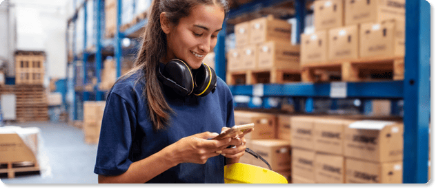 female frontline worker using her iphone in a distribution center