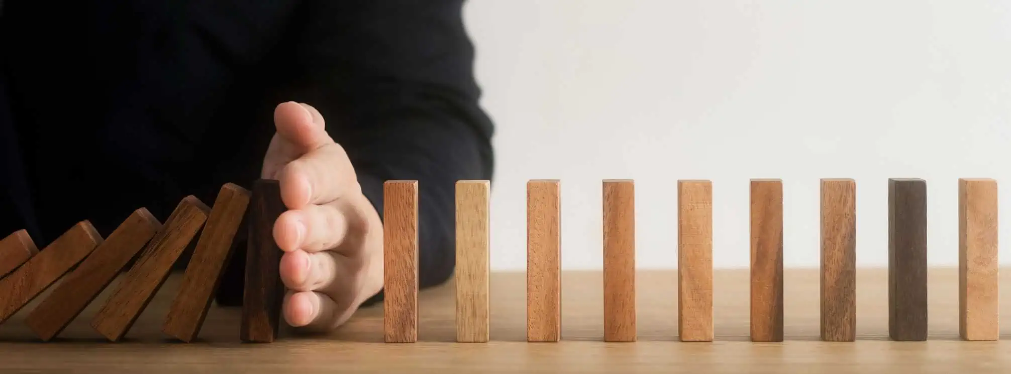 man catching dominoes from falling and knocking down the rest of the dominoes