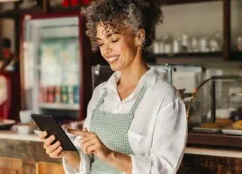 female hospitality employee smiling as she uses a phone