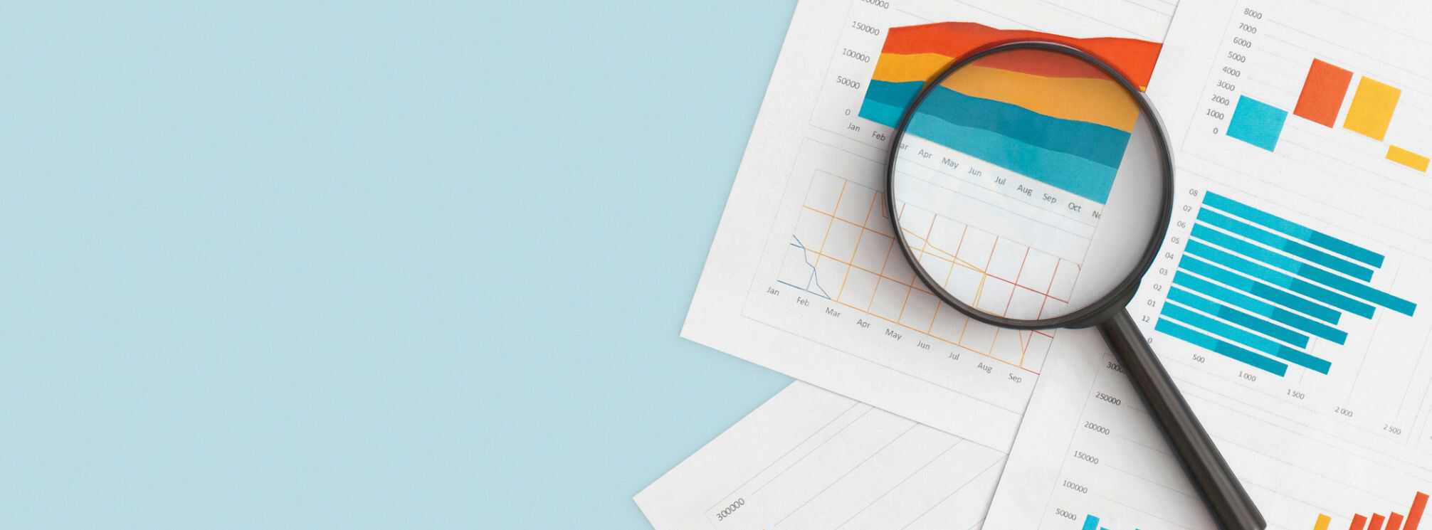 magnifying glass over papers with analytics charts on them