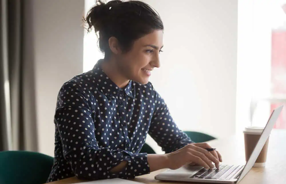 female internal communications professional working on a laptop using our internal comms content management system