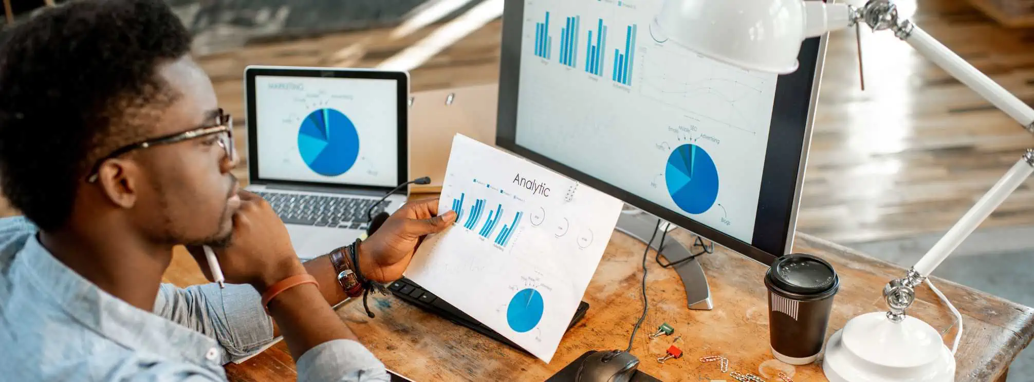 young black professional looking at computer screens with various graphs and data visualizations on them