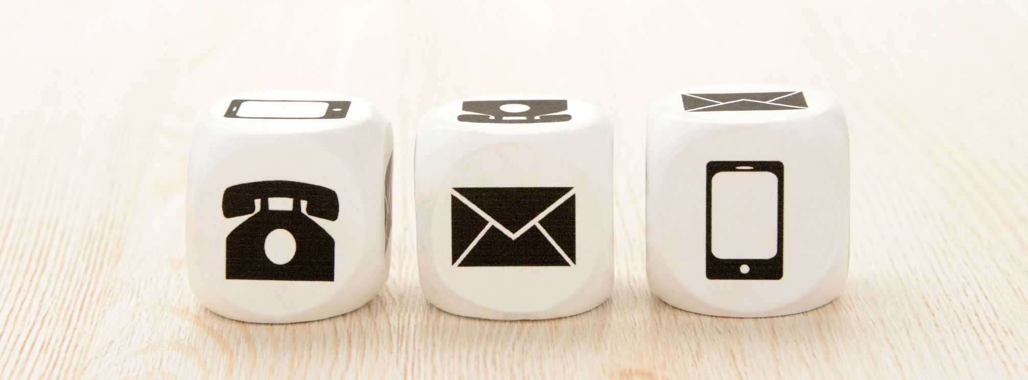 three wooden blocks with icons for telephone, email, and mobile employee apps, which are all types of employee communication tools