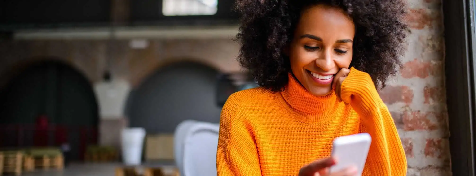 Remote employee working in a coffee shop and checking a company text message on her phone