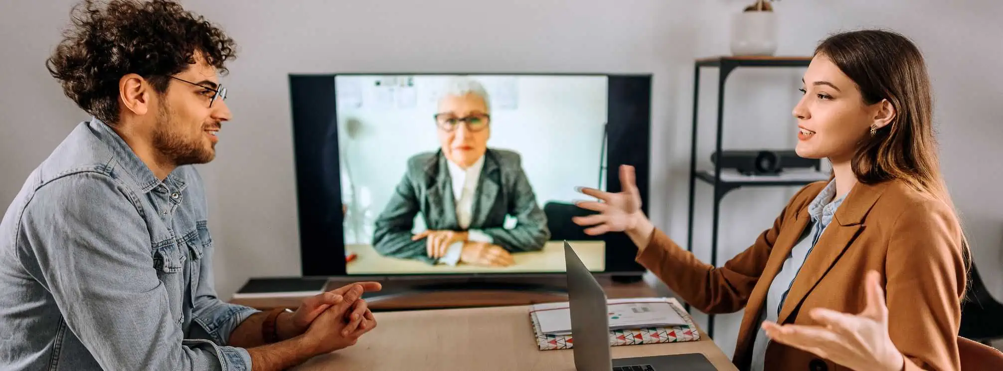 three hybrid employees working together. Two are in office and highly engaged with each other, but are ignoring the third employee who is remotely dialed in.