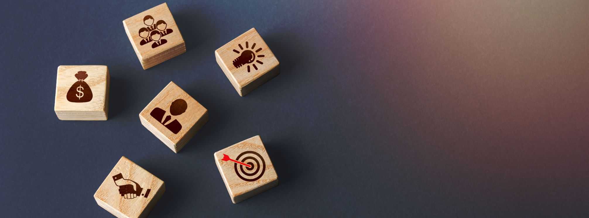 6 wooden blocks each with a different HR-related icon on them, like goals, compensation, talent, and innovation