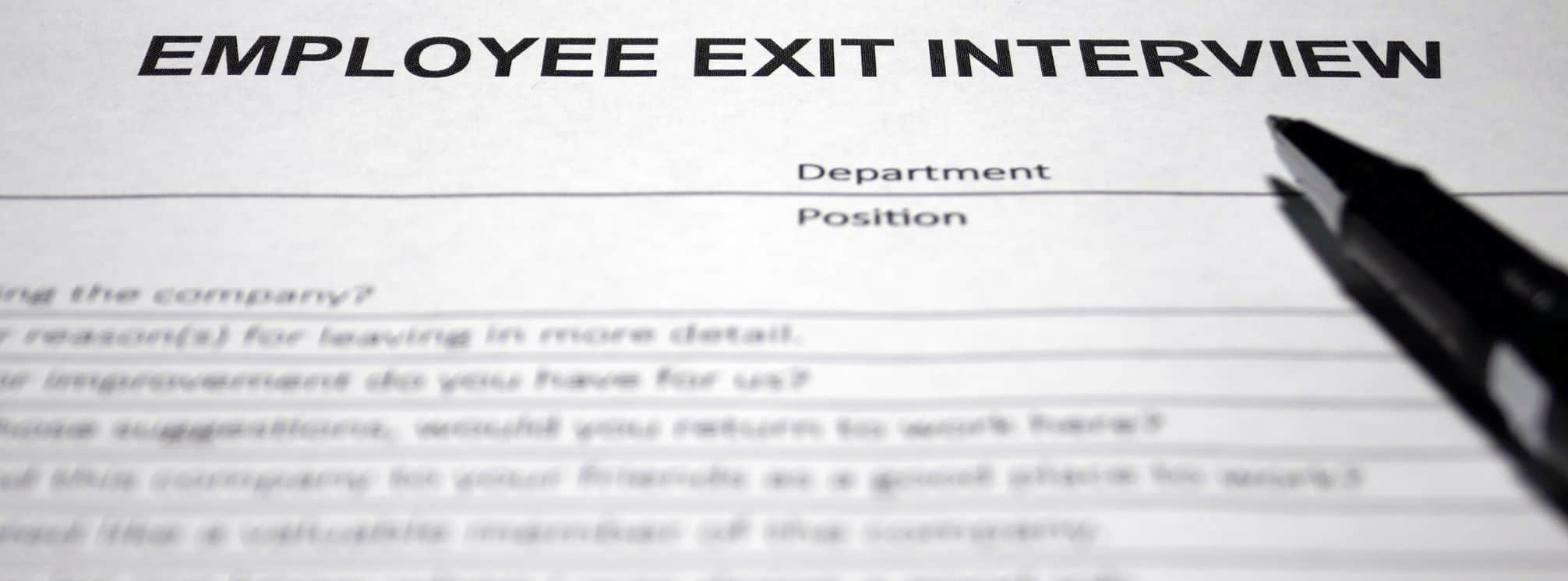photo of a printed survey that says "employee exit interview" at the top with a pen resting on the paper