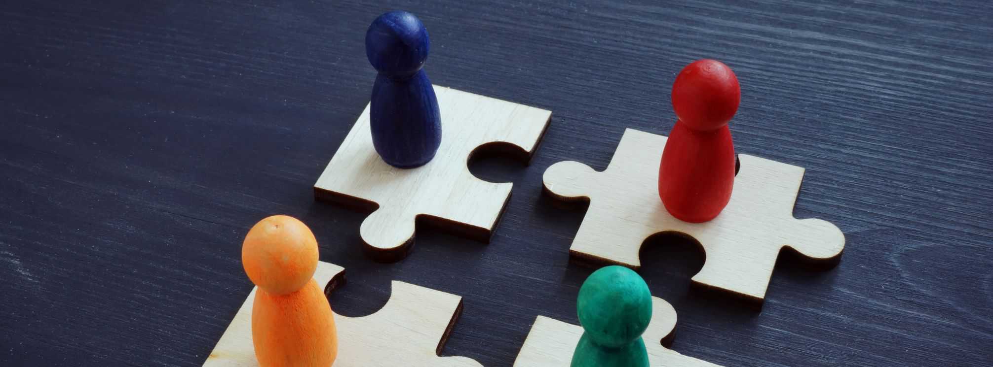 4 puzzle pieces aligned to connect with multi-color wooden pegs on top of them