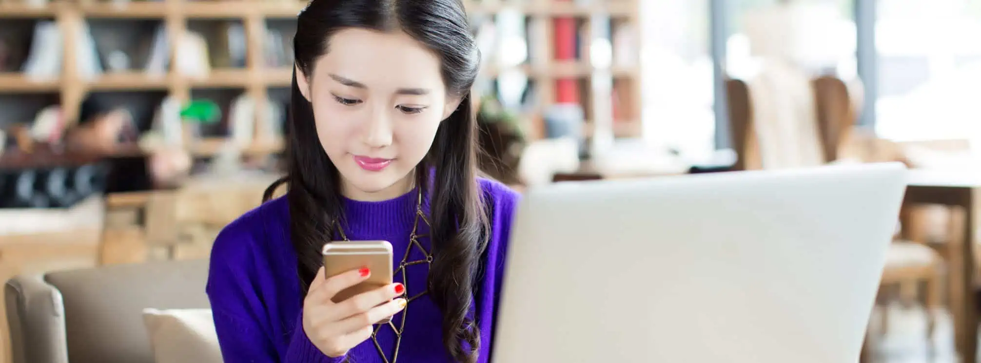 Young asian woman checking her employee app while working at her desk in her remote office