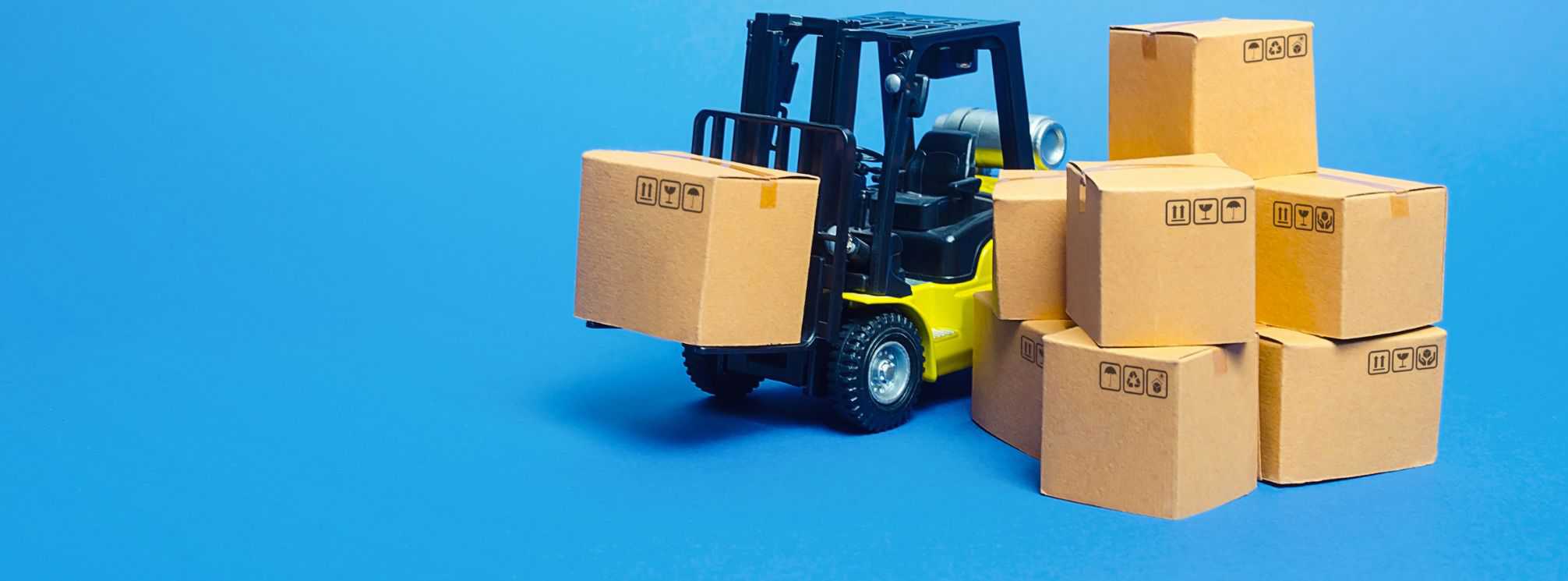 Model of a forklift lifting a box with a stack of boxes next to it.