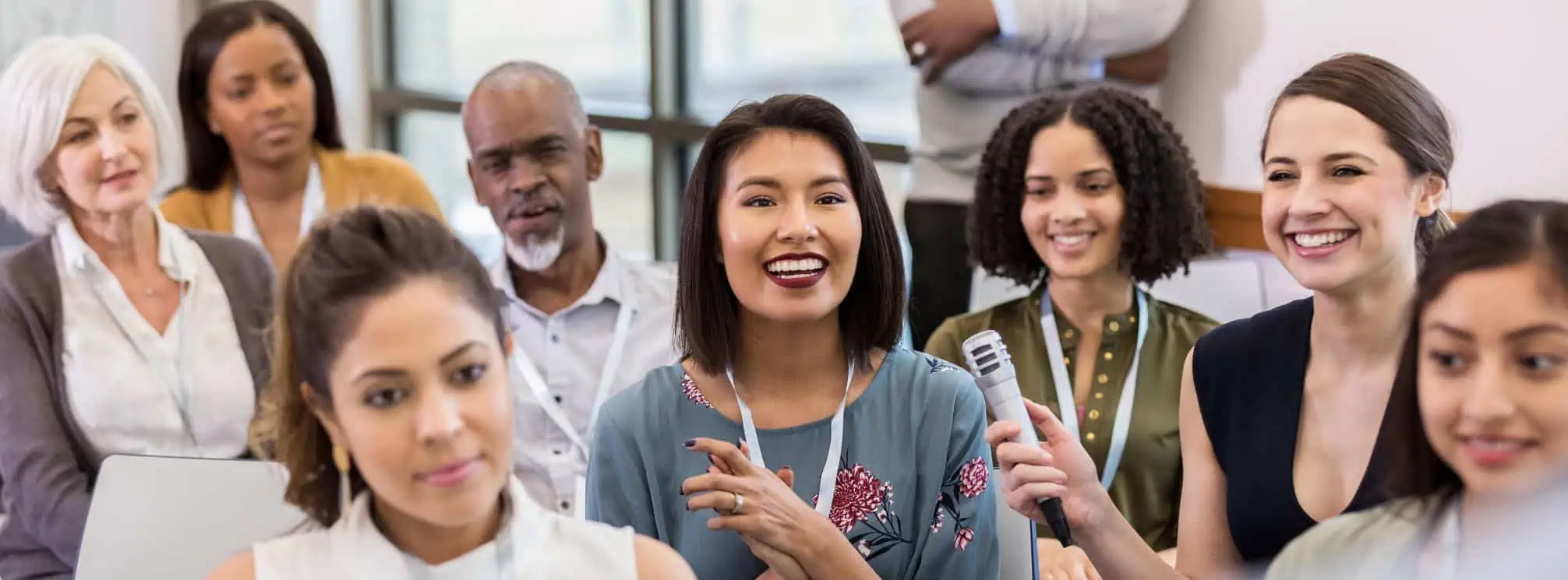 Employee audience at an all-hands meeting with a microphone passing around for audience questions