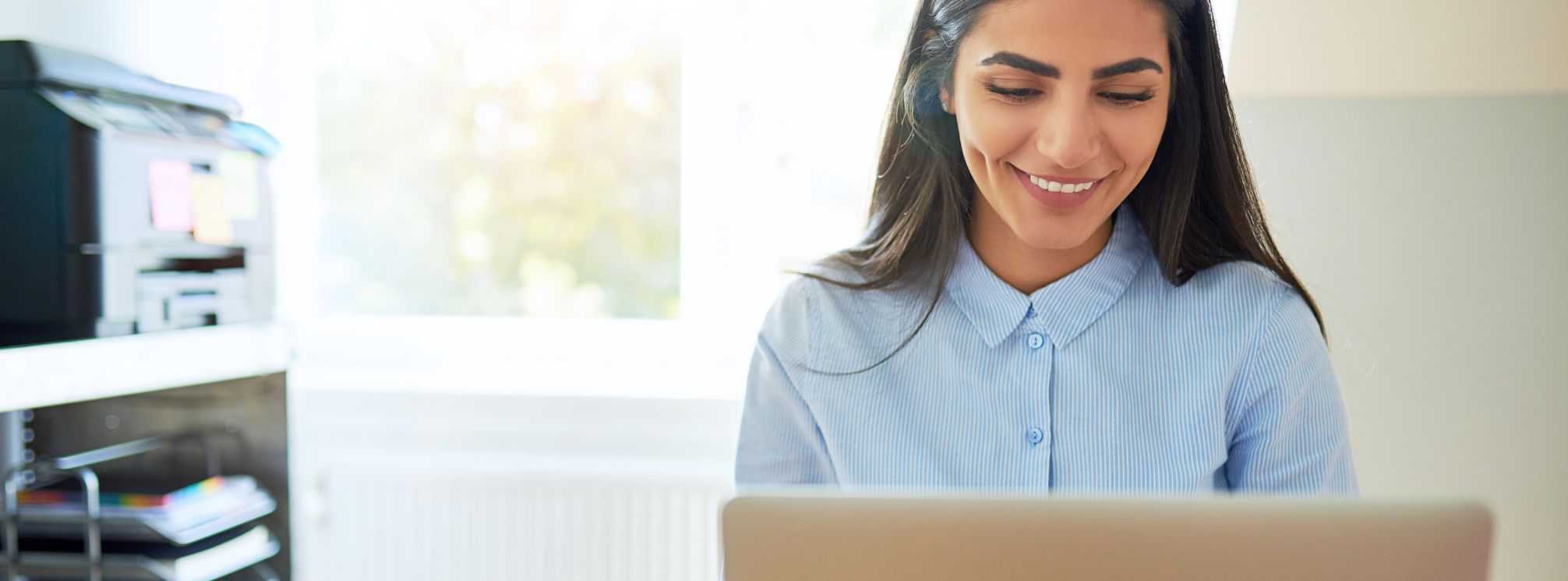 A female employee smiling and engaged in her work on her laptop.