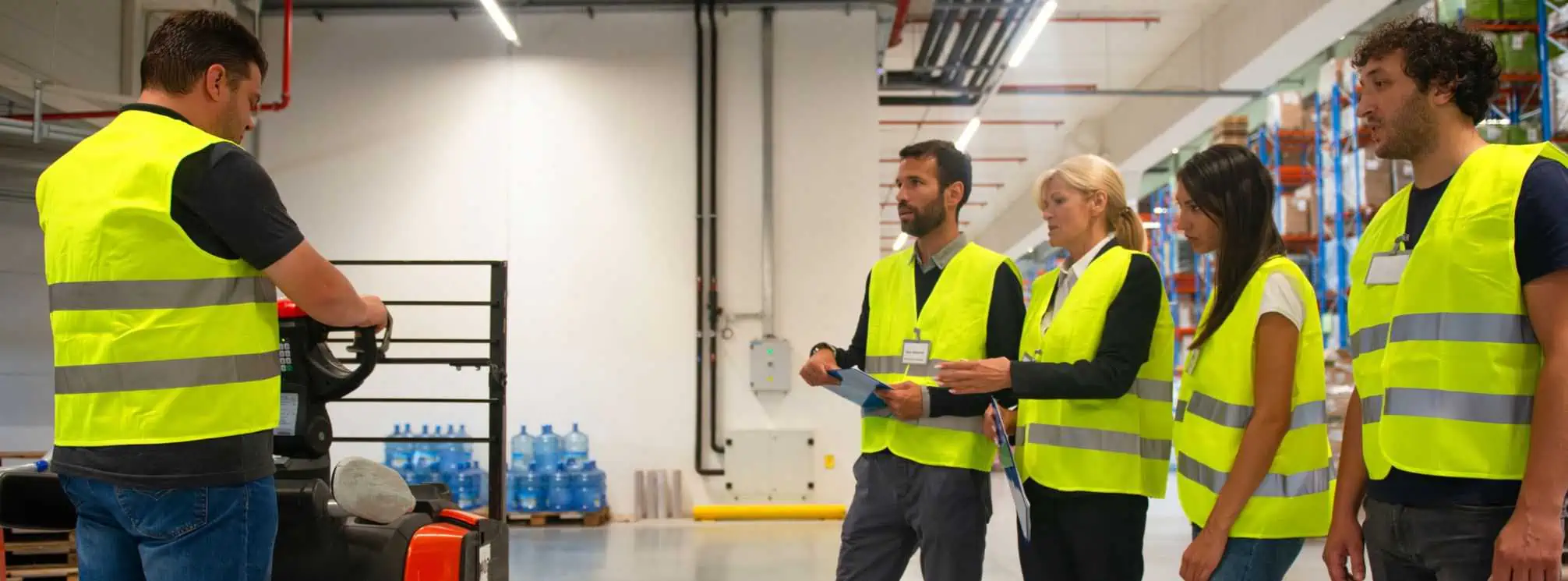 Four warehouse workers being trained on forklift safety in their Onboarding session 