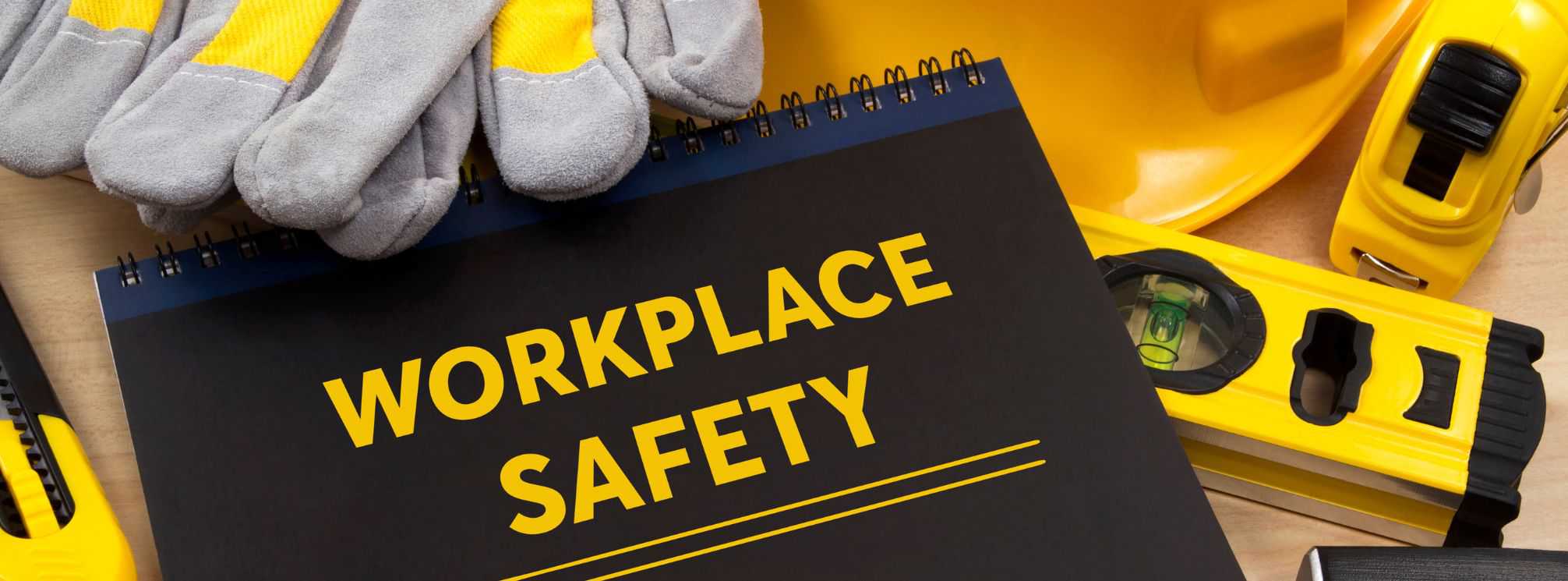 Workplace safety tips manual sitting on a pile of safety equipment like gloves and a level.