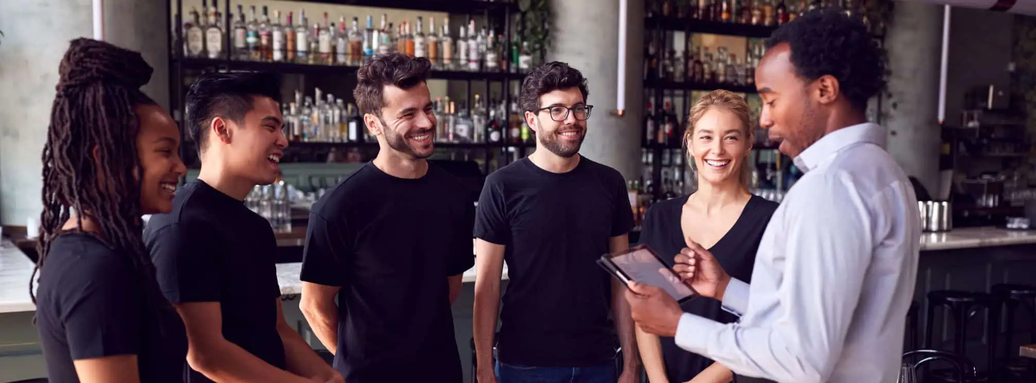 Restaurant team having a shift meeting together by the bar.