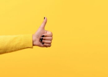 Bright yellow background with a woman's arm reaching out to give a thumbs up.