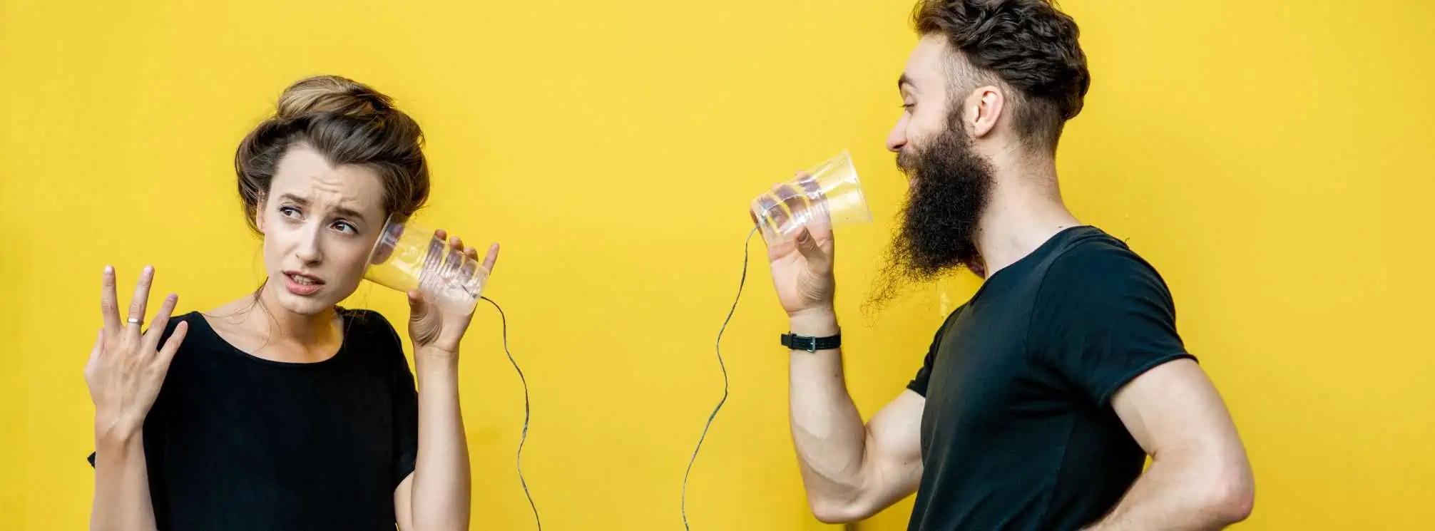 Two people playing the game of telephone and looking very confused.